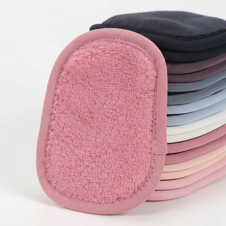 A hand holding a reusable facial cleansing pad, gently removing makeup, skincare essential