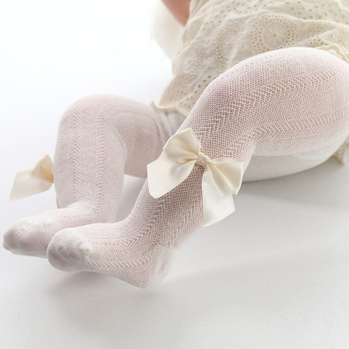 Soft pink baby tights featuring a cute bow detail, ideal newborn fashion for baby girls.