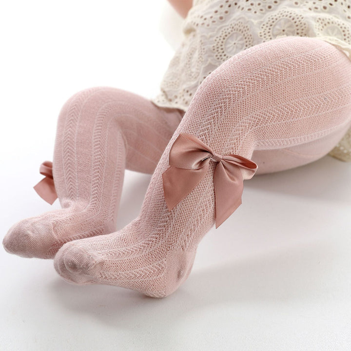 Baby girl's soft pink cotton blend tights with a small decorative bow on the ankle, perfect for spring and autumn comfort.