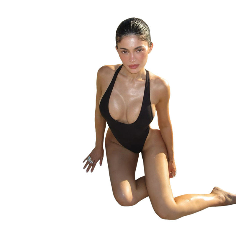 Women's black one-piece swimsuit featuring a deep neckline & figure-hugging cut. Ideal for summer beachwear.