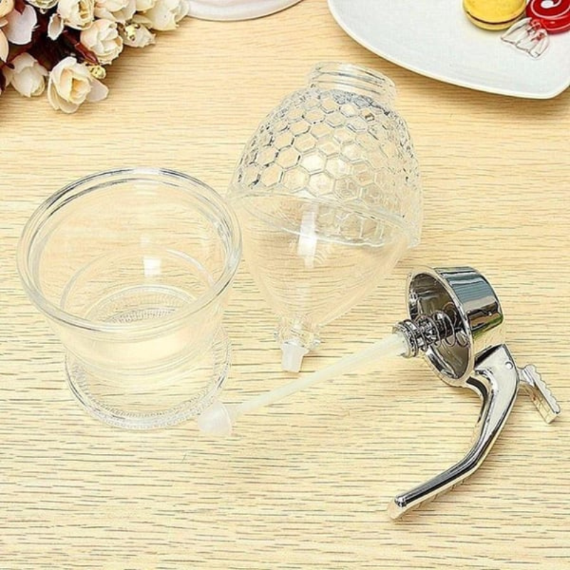 Modern clear plastic drip-free honey dispenser with stand, an essential kitchen tool for easy, clean syrup serving.