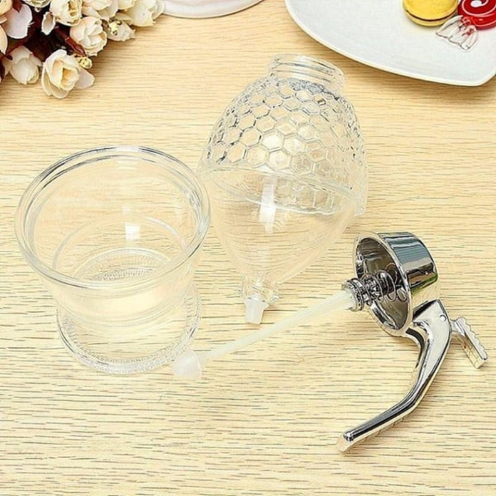 Modern clear plastic drip-free honey dispenser with stand, an essential kitchen tool for easy, clean syrup serving.