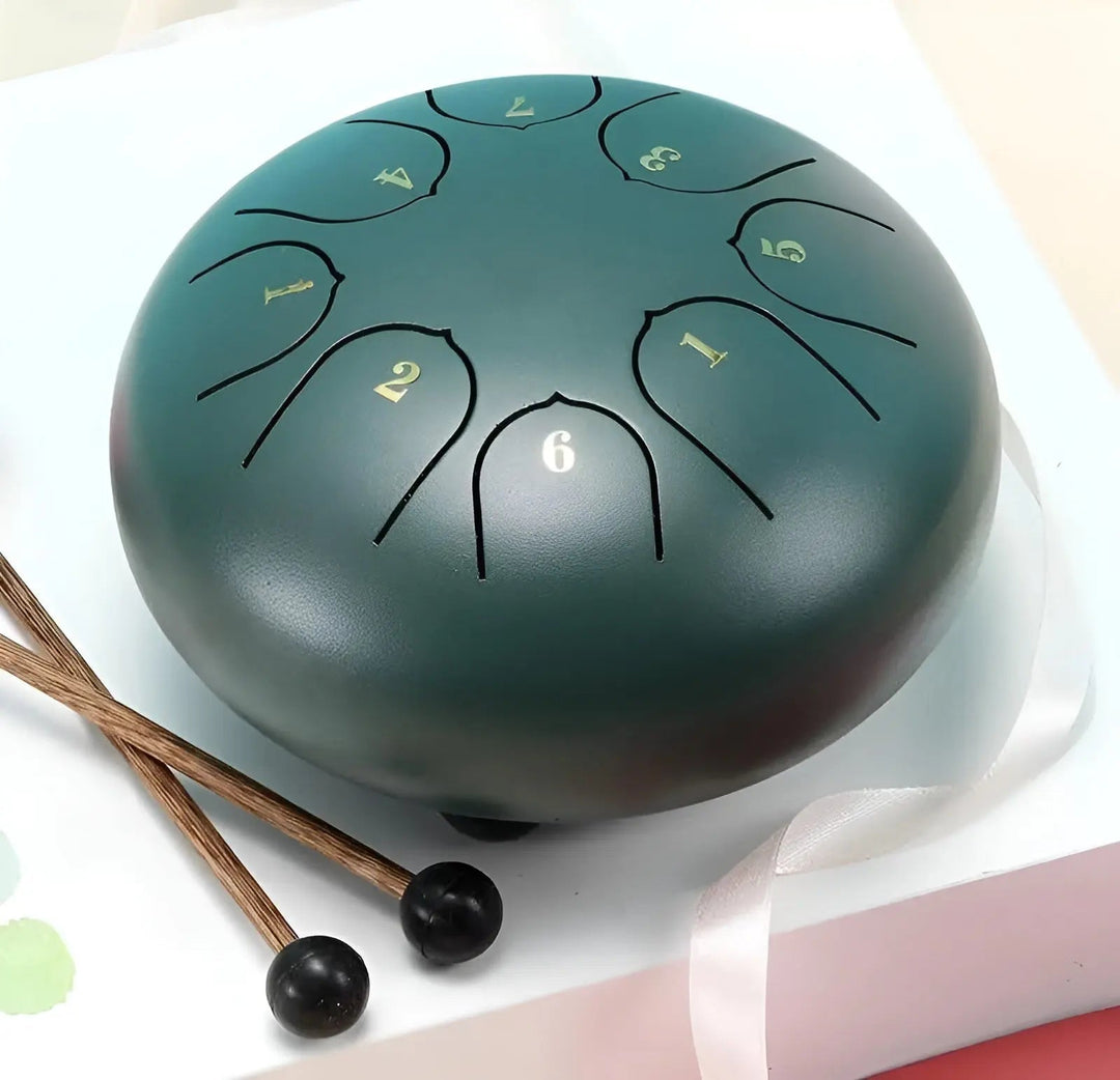 Hands gently playing a dark grey steel tongue drum, promoting relaxation & mental peace.