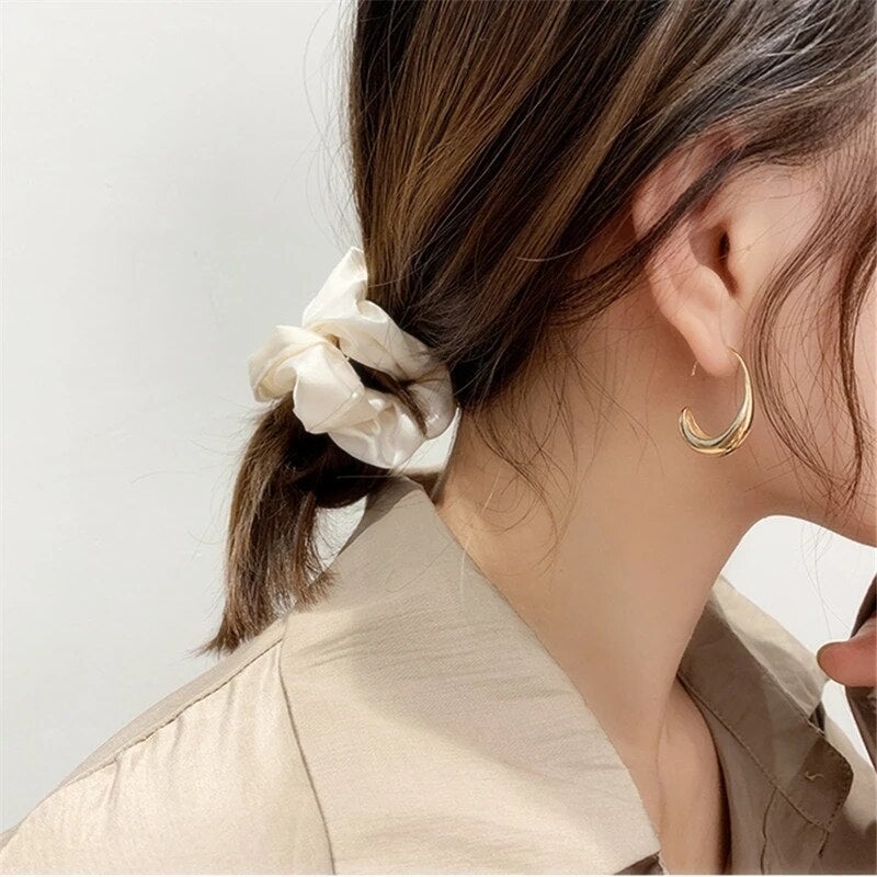 Close-up of Celeste women's elegant dangle earrings in shimmering gold and silver, luxury fashion accessory.
