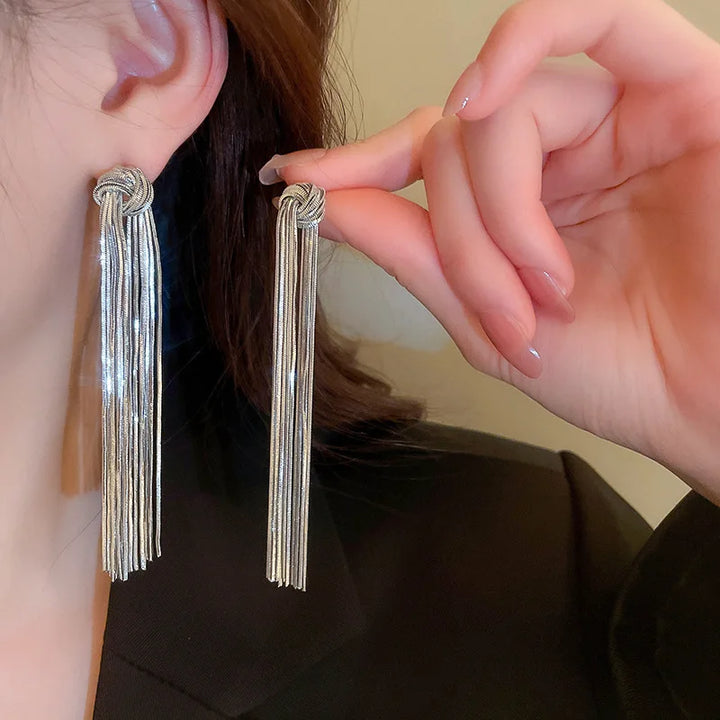 Women's elegant knot design long tassel earrings with flowing metallic chains.