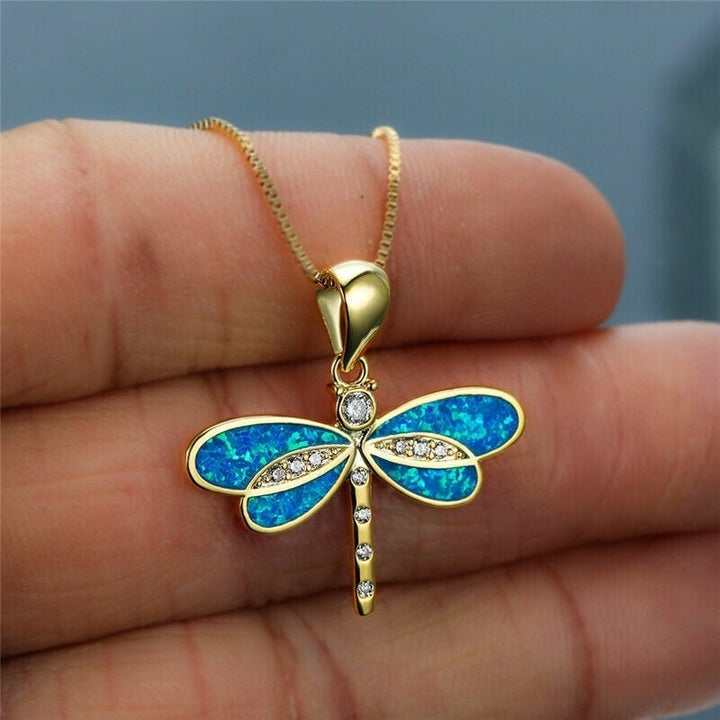 Close-up of a women's gold dragonfly pendant necklace with a brilliant opal accent. Luxury nature-inspired jewelry.