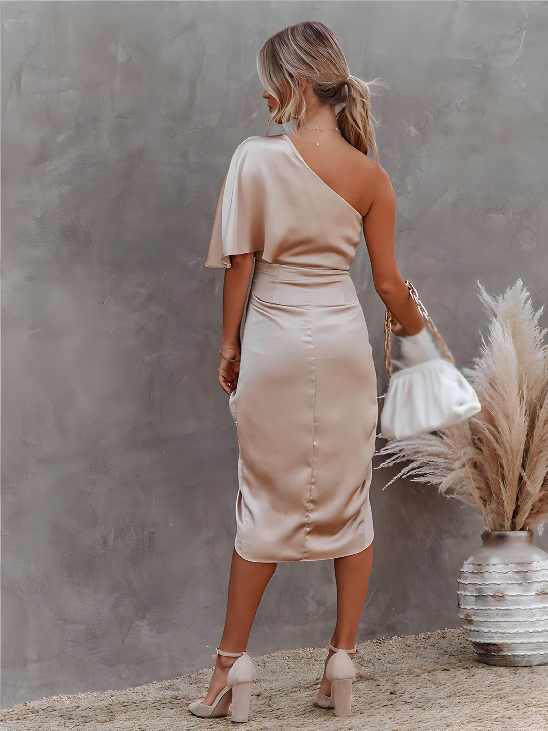 Side view of an elegant one-shoulder special occasion dress, asymmetrical design, 3/4 sleeve.