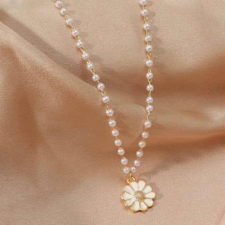Close-up of a women's elegant pearl & daisy pendant necklace, showcasing fine floral silver jewelry.