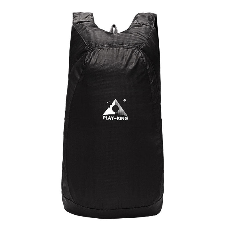 Happy hiker wearing a 20L foldable water-resistant backpack on a scenic mountain trail.