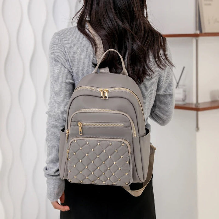 Lifestyle shot of a black water-resistant nylon backpack for women amidst urban environment.