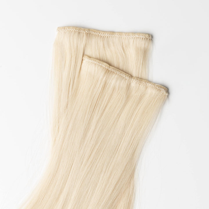 Premium human hair clip-in extensions in light ash blonde, easy to apply for women's hair volume.