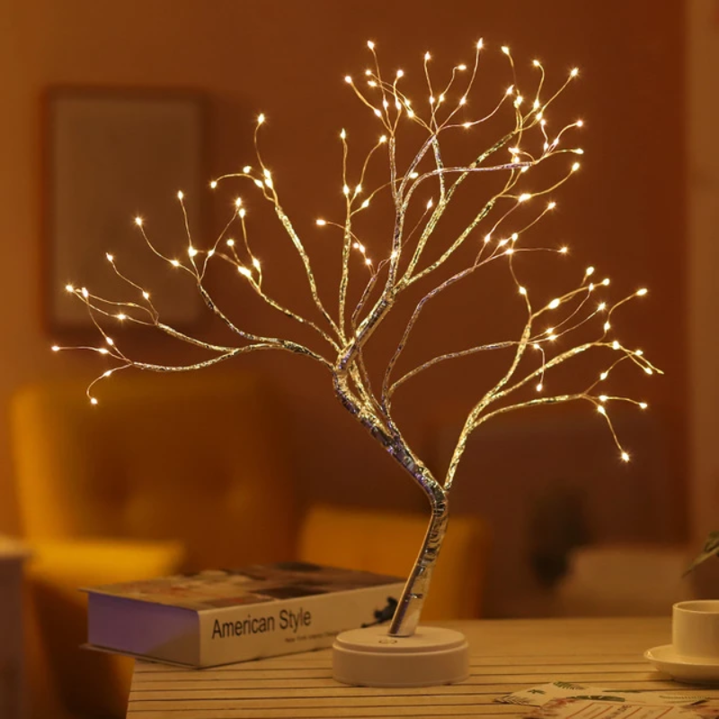 Decorative LumaTree LED tree lamp, casting a soft glow, ideal for ambient lighting and home decor on a bedside table.