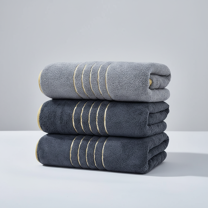 Stack of folded LuxuryWrap microfiber bath towels in a clean, minimalist bathroom setting.