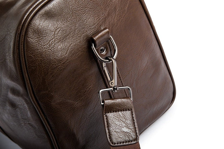 Back view of a men's black leather travel duffel, emphasizing its comfortable, detachable shoulder strap