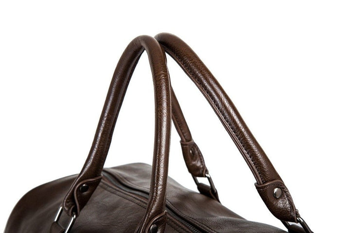Men's brown leather carry-on duffel bag modeled by a man, illustrating its size and sophisticated look