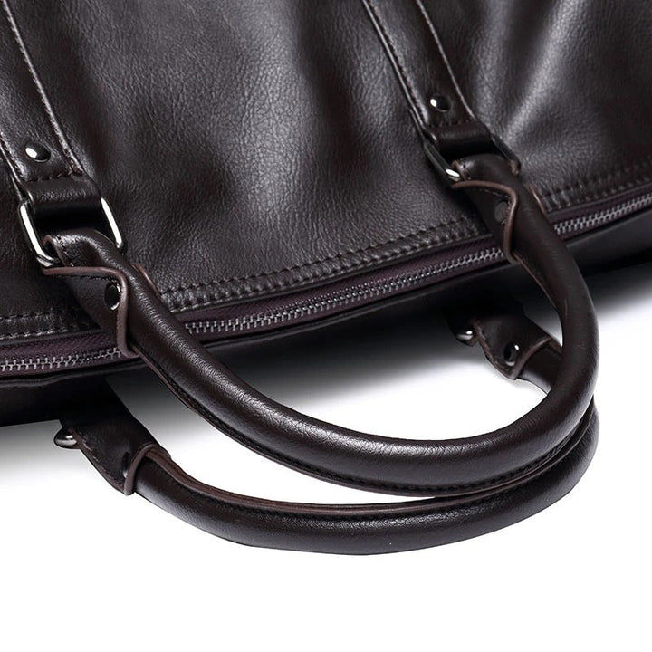 Men's leather travel bag in black, handheld by a stylish man, emphasizing its carry-on functionality