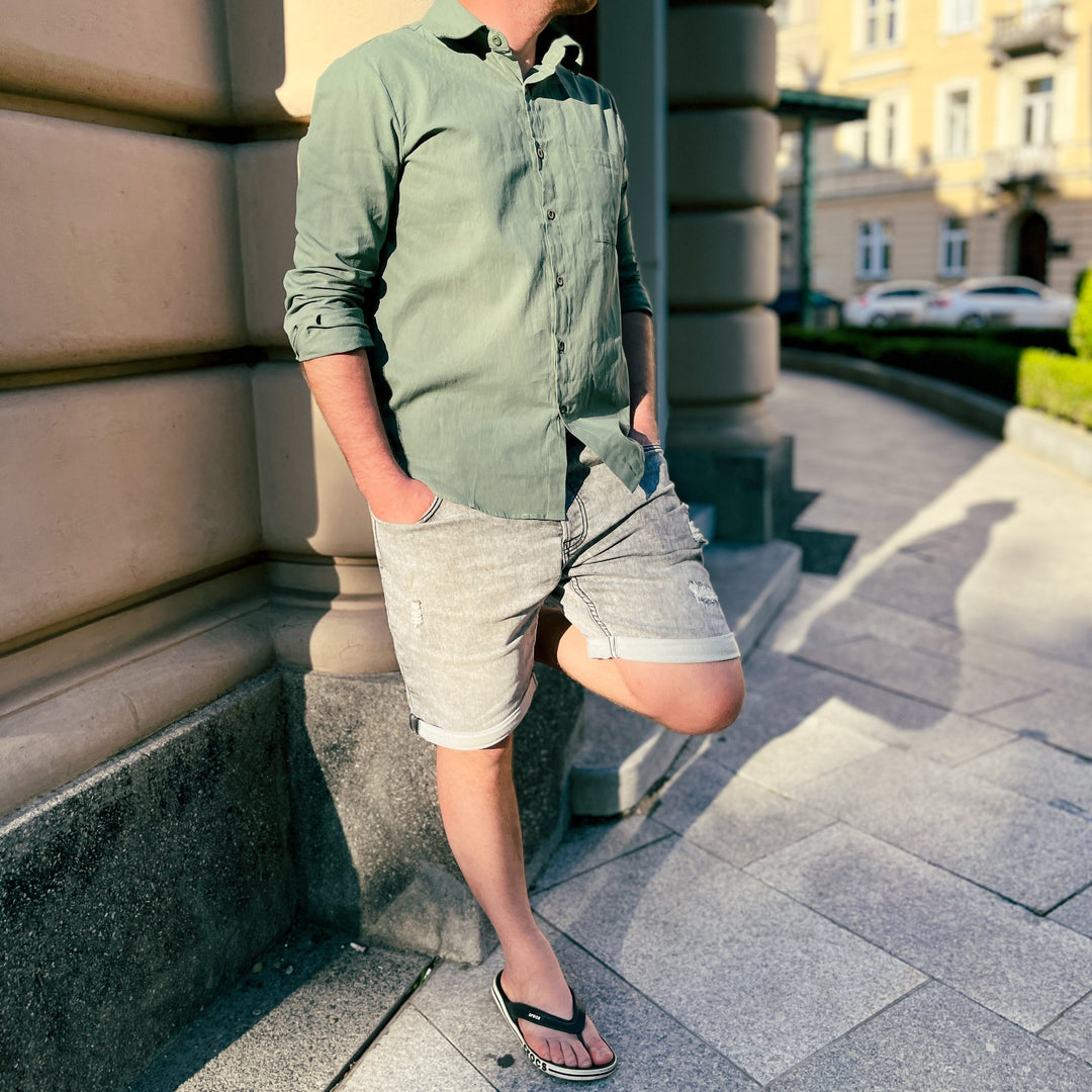 Men's breezy short-sleeve button-up shirt on a beach, essential for vacation & summer style.