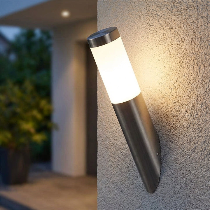 Modern LED motion sensor outdoor wall sconce, elegant black finish, illuminating a pathway.