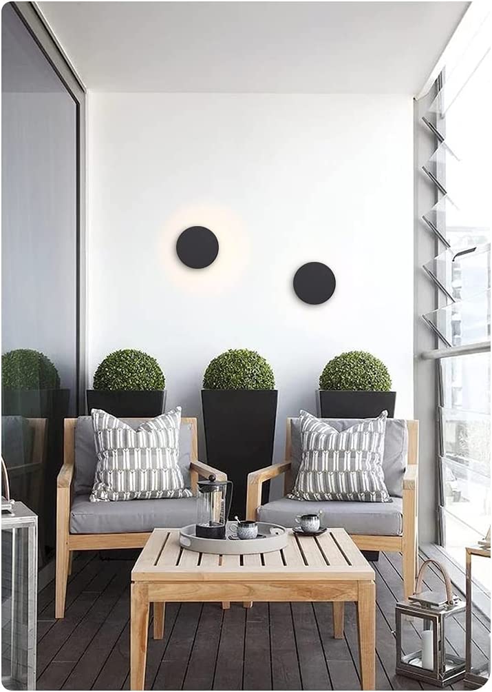 Modern round outdoor wall light by Solunex, casting soft ambient light for a garden