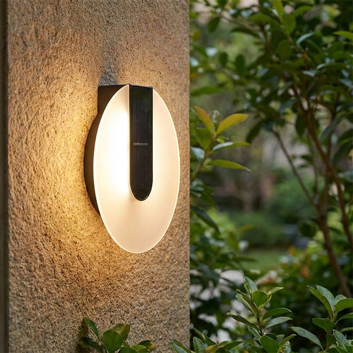 Modern Solenyx outdoor round LED wall sconce, weatherproof, illuminating a patio area