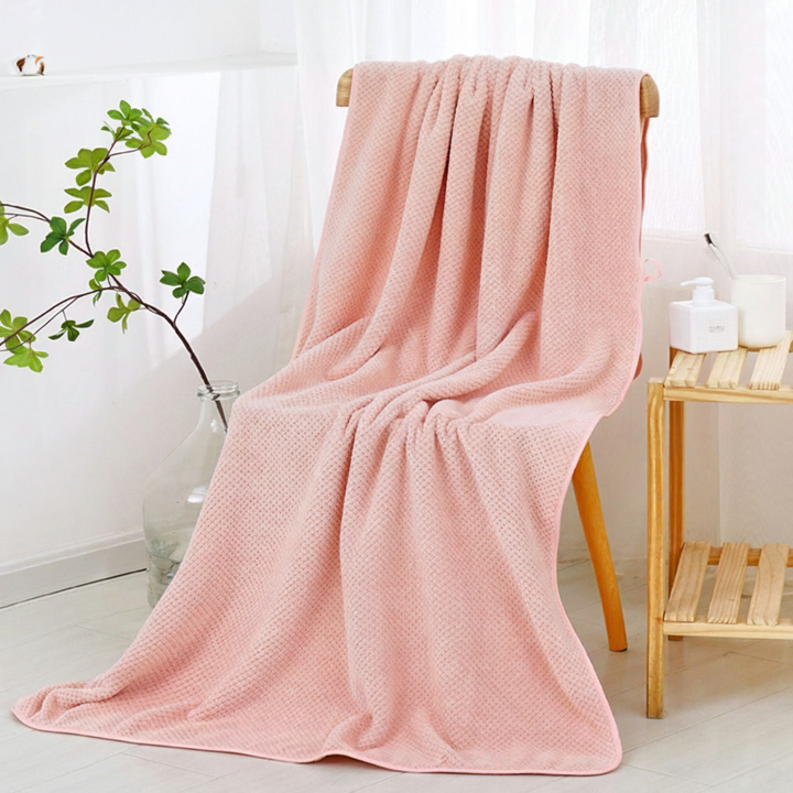 Folded coral fleece bath towel showing its plushness and quick-dry properties, a bathroom essential.