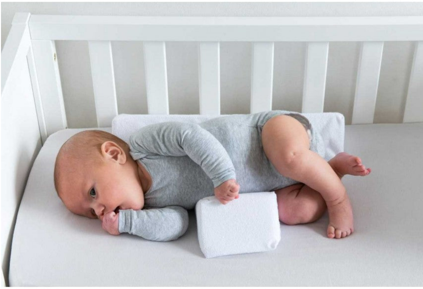 Grey adjustable anti-roll baby side sleep pillow. Essential newborn infant care product for safe and supported sleep.