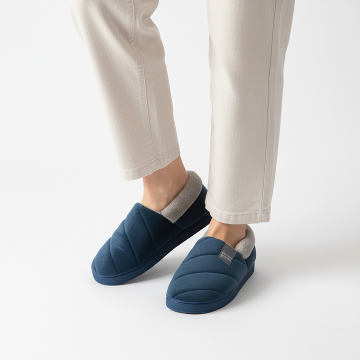 Women's hands holding a pair of soft, fleece-lined slippers, emphasizing the comfort and warmth