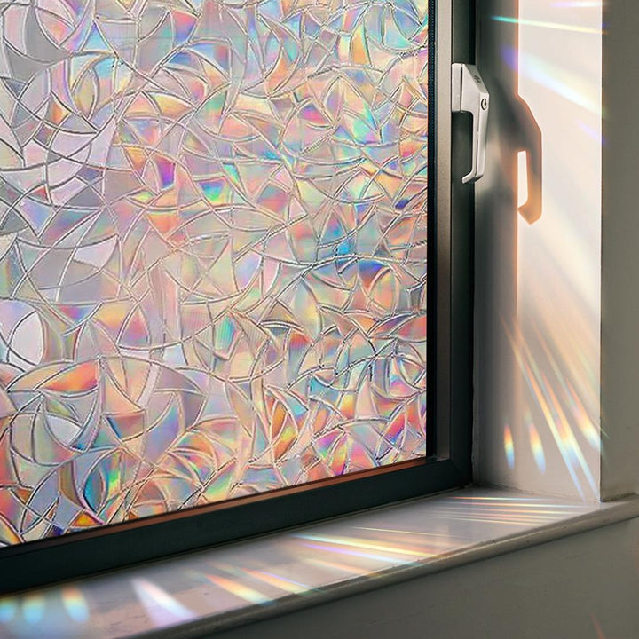 Circular rainbow prism window decal adhering to glass, generating vivid light patterns on an interior wall.
