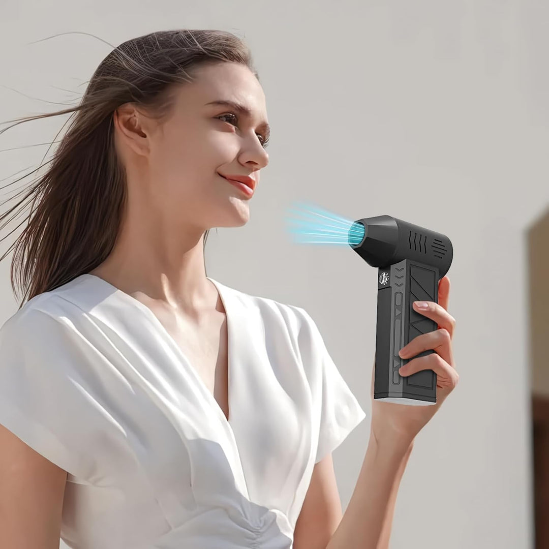 Compact rechargeable air duster next to a laptop, emphasizing its use for electronics