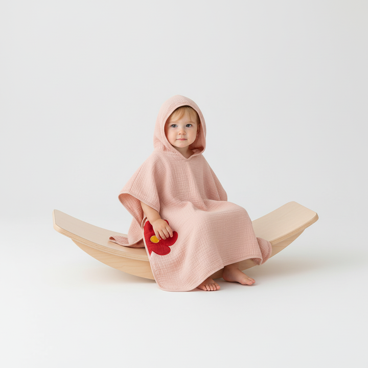 Child wearing a comfortable muslin hooded poncho, essential for kids' bath time and beach