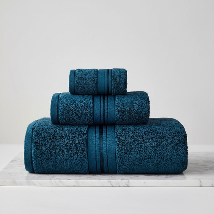 Neatly folded stack of soft cotton towels, including bath towel, hand towel, and washcloth, home good