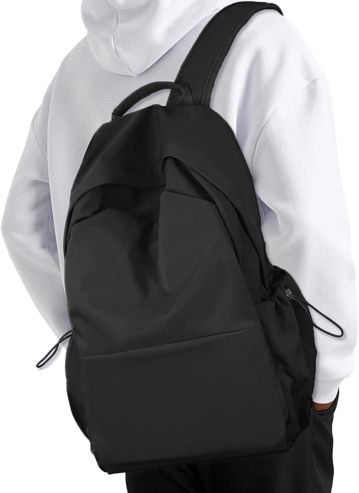 Black lightweight water-resistant travel backpack next to a laptop and notebook