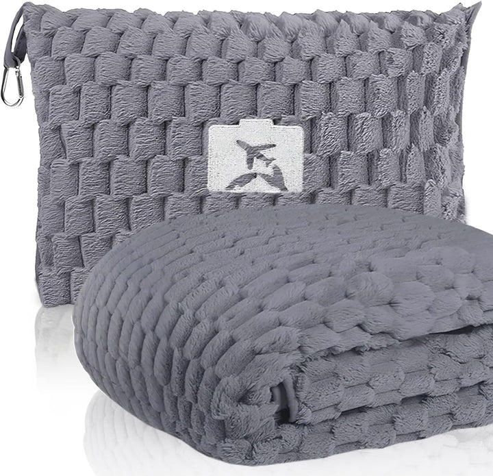 Woman using gray flannel travel blanket and pillow on an airplane, comfortable travel gear