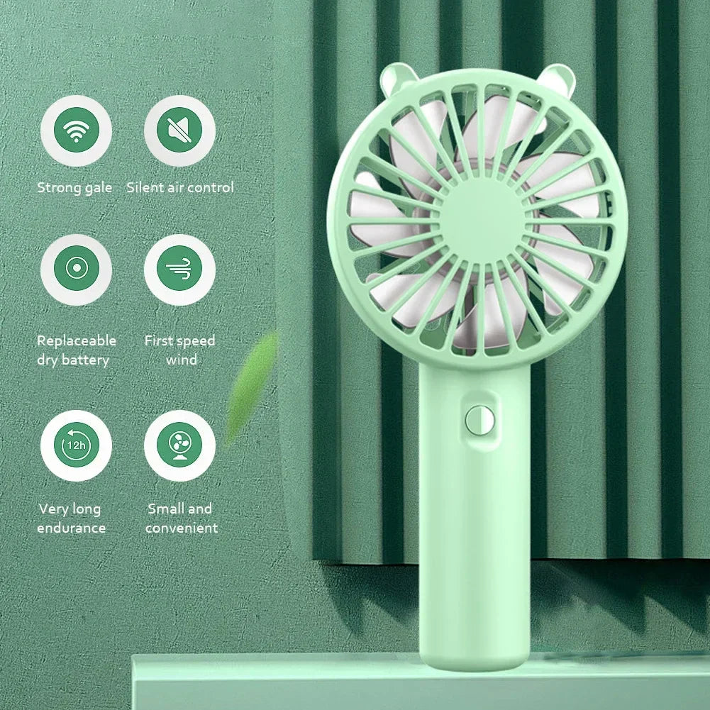 Veyra mini handheld fan charging via USB cable connected to a laptop, showcasing its convenient rechargeable function