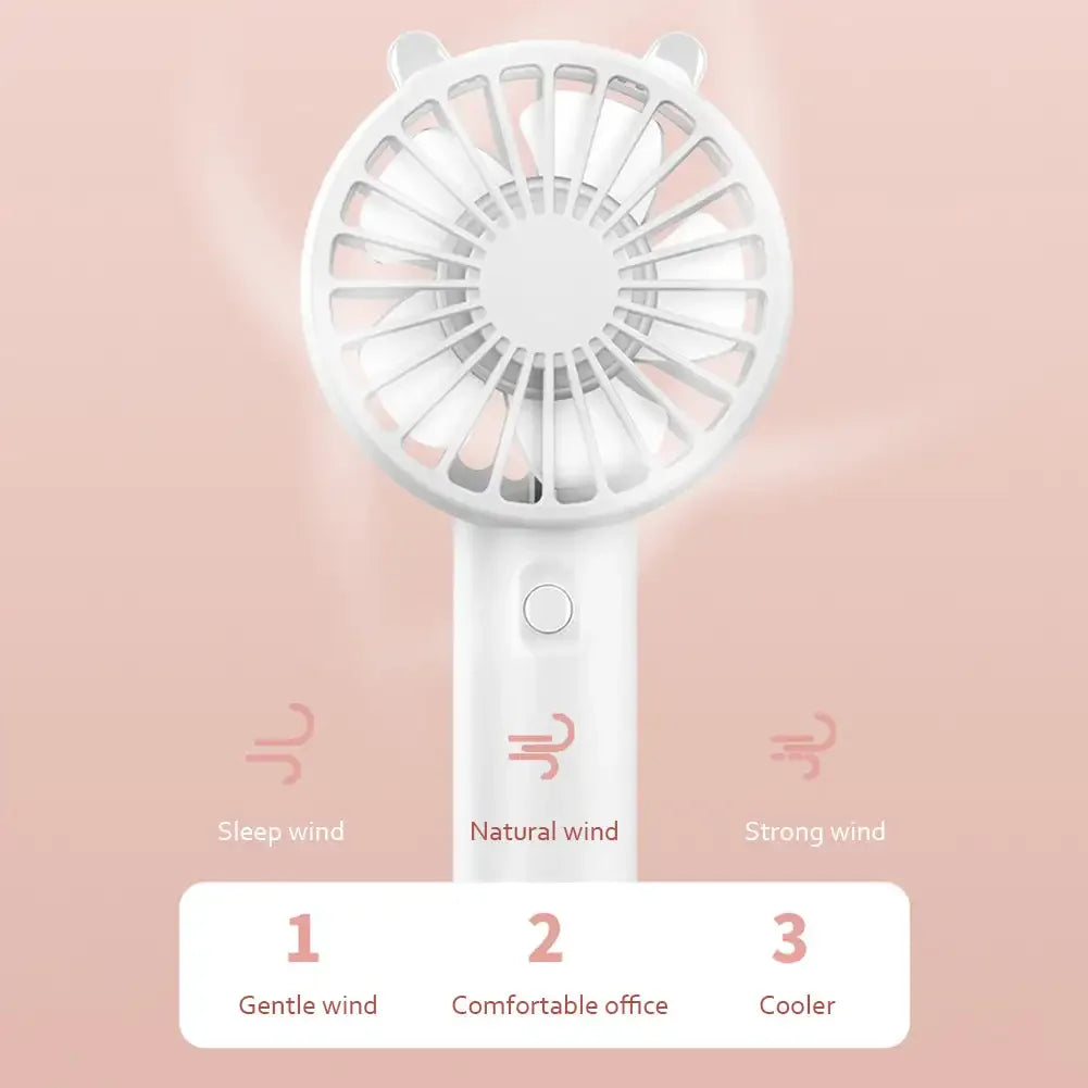 Portable USB rechargeable mini desk fan, standing upright on a table next to a computer, for office or home use
