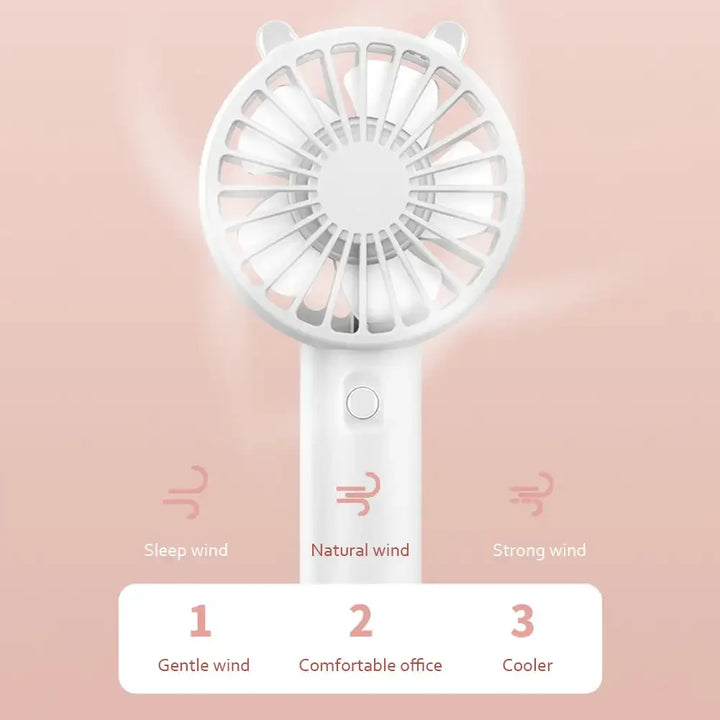Portable USB rechargeable mini desk fan, standing upright on a table next to a computer, for office or home use