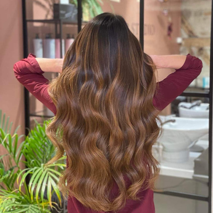 Women's warm brown balayage tape-in human hair extensions, enhancing natural volume, length & style.