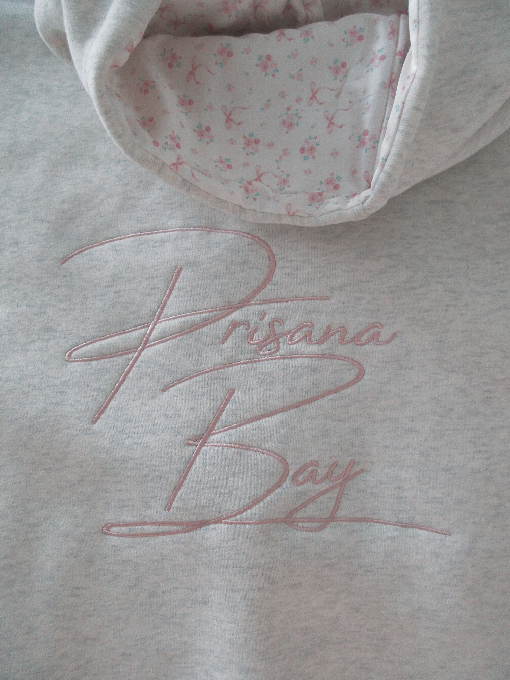 White Elodie women's hoodie, relaxed fit, soft fabric, with a charming pink bow detail. Casual & cozy.