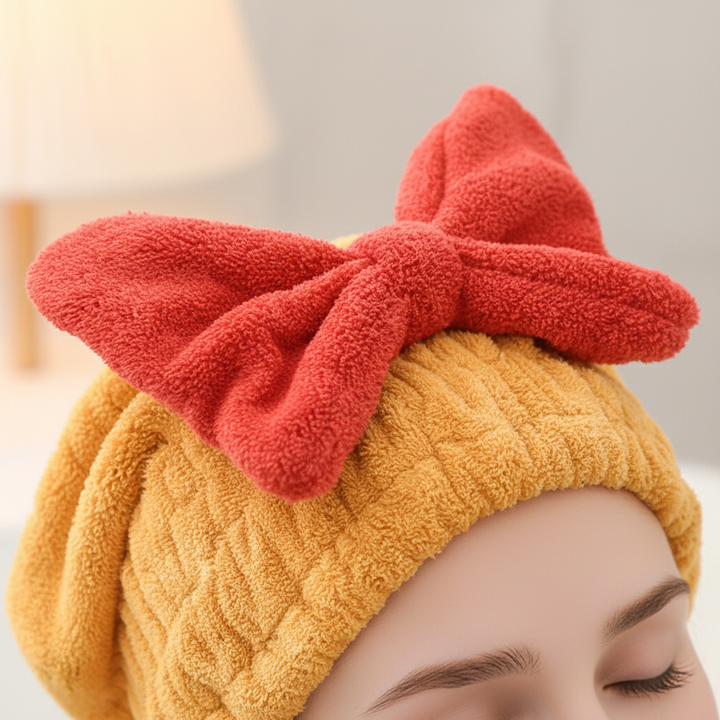 Three damp microfiber hair drying towel wraps in pink, blue, and white, neatly folded on a wooden surface.