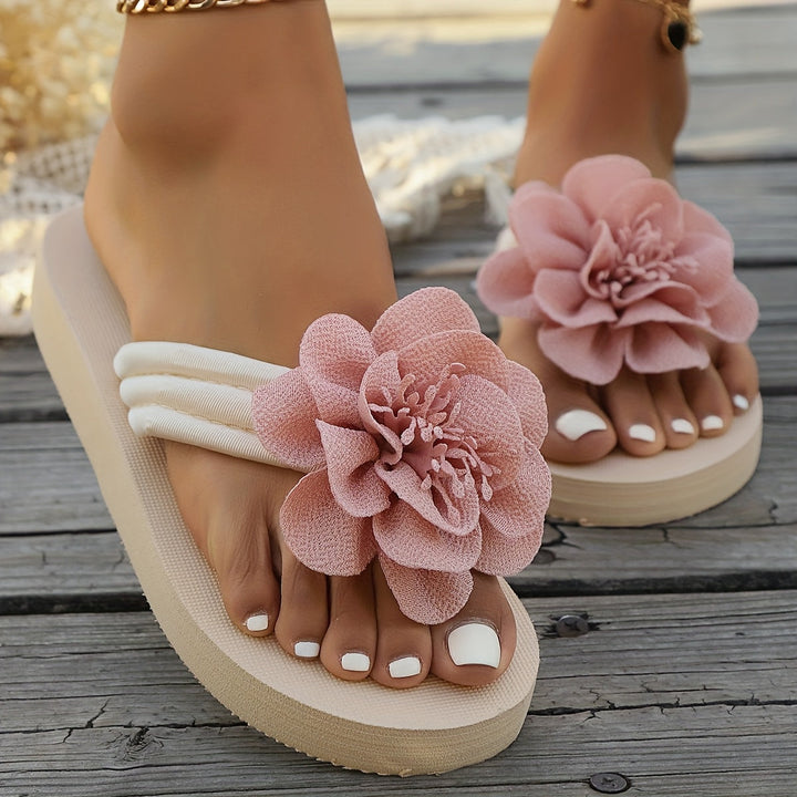 Lady wearing pink floral detail slippers, standing on a wooden deck, casual, comfort footwear