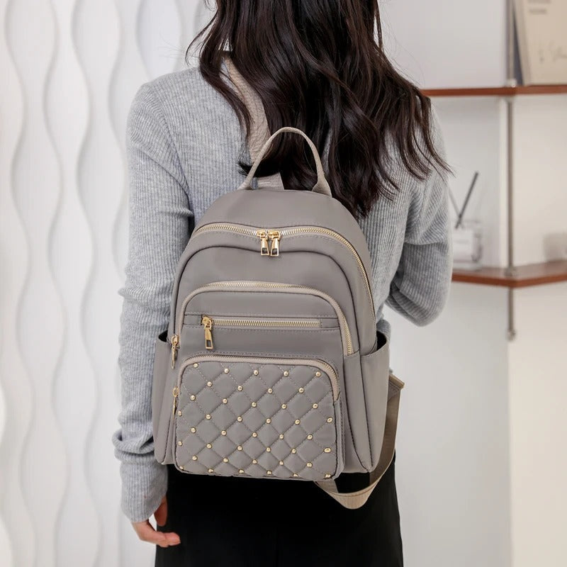Stylish women's lightweight nylon backpack next to a cafe. Versatile water-resistant bag for daily carry & urban adventures.