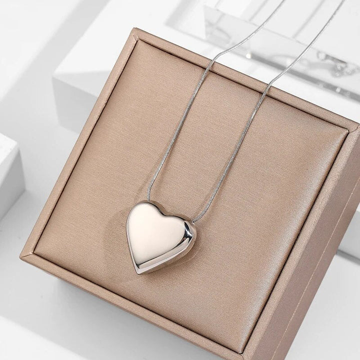 Close-up of a minimalist peach heart pendant necklace. Delicate stainless steel, elegant women's jewelry, simple design.