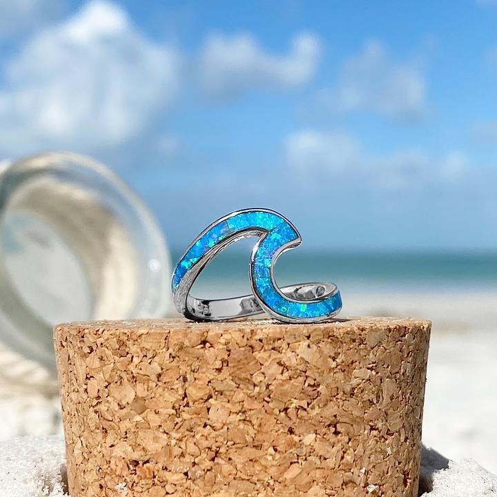 Women's silver sea wave ring with vibrant blue opal gemstone, elegant ocean-inspired jewelry.
