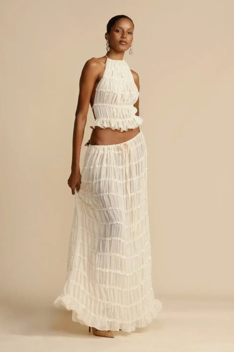 Sleeveless women's halter top and pleated maxi skirt two-piece set, a trendy and flowy summer fashion outfit.