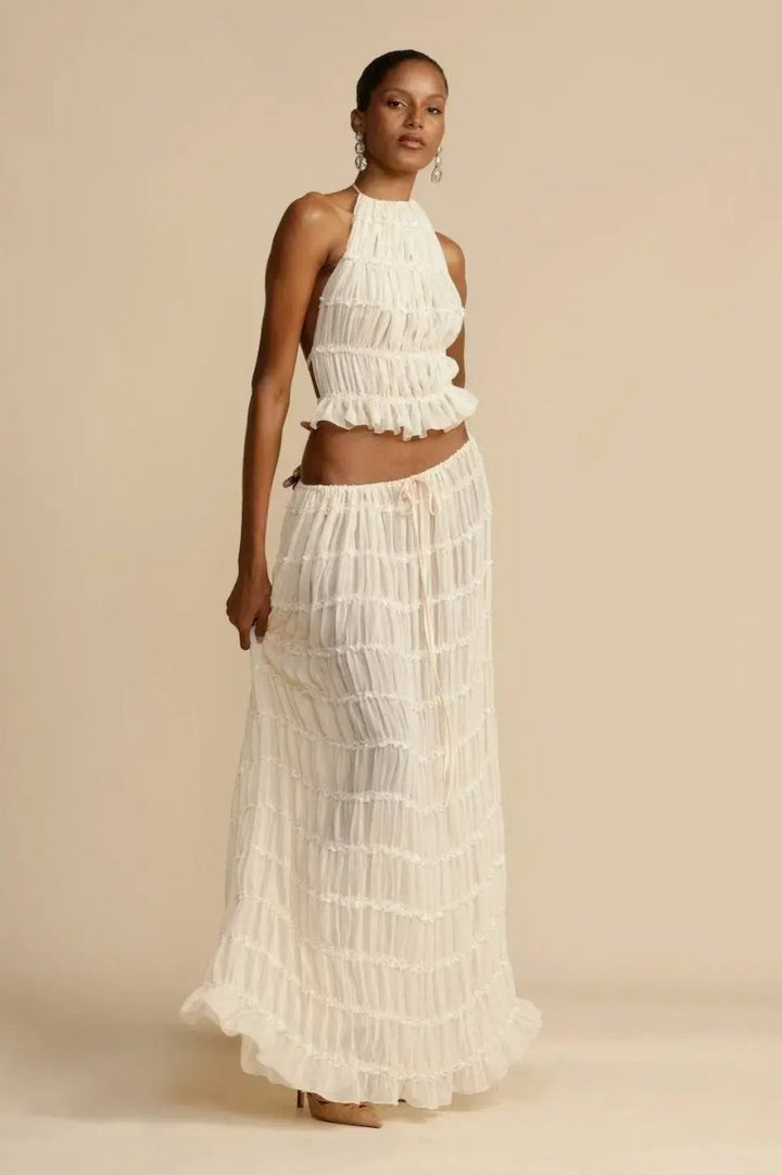 Sleeveless women's halter top and pleated maxi skirt two-piece set, a trendy and flowy summer fashion outfit.