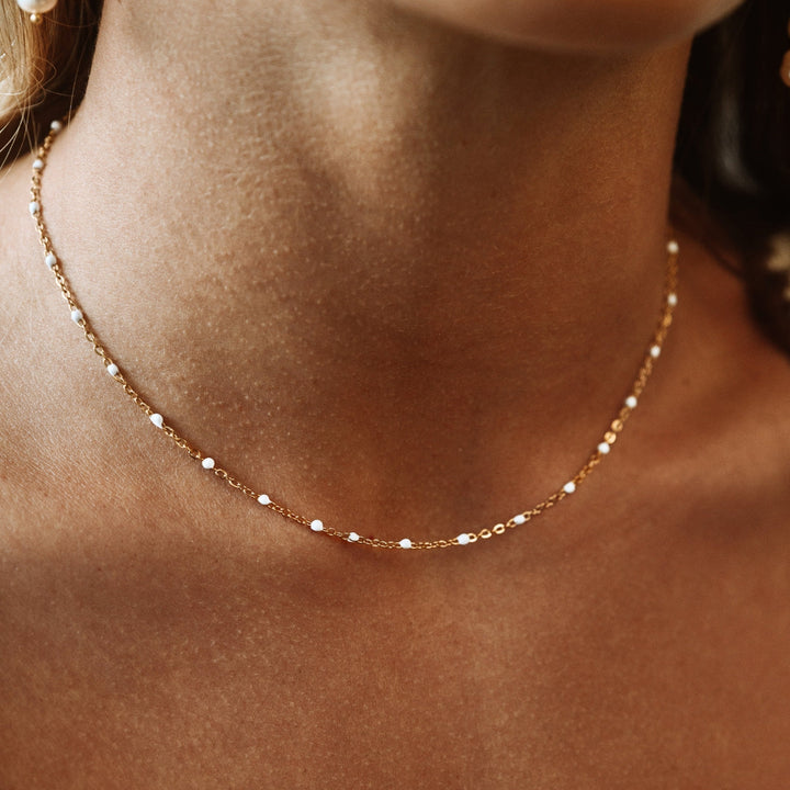 Women's white enamel bead choker necklace. Elegant, minimalist fashion jewelry.