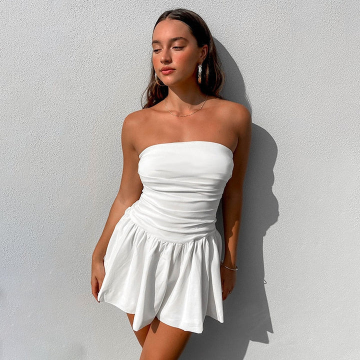 Feminine white strapless mini dress featuring stylish pleats, ideal for a summer party or evening event.